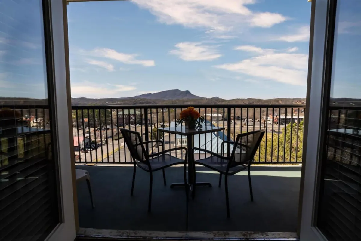 The image showcases a private balcony featuring a cozy table adorned with fresh flowers and inviting chairs, all set against a backdrop of sweeping mountain views. The scene is tranquil, evoking a sense of relaxation and connection with nature—perfect for sipping morning coffee, unwinding in the afternoon, or stargazing in the evening.